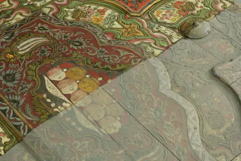 Ein zur Hälfte restauriertes Kunstobjekt mit Verzierungen und Obst.