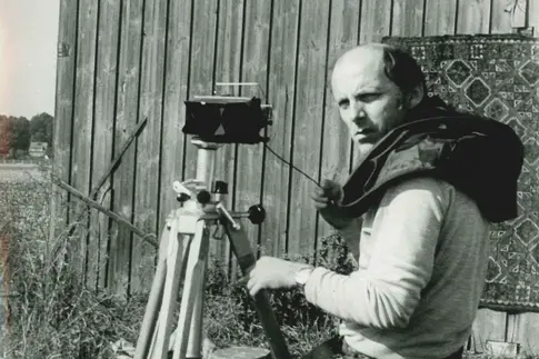 Ein Mann mit einer auf einem Stativ stehenden Kamera