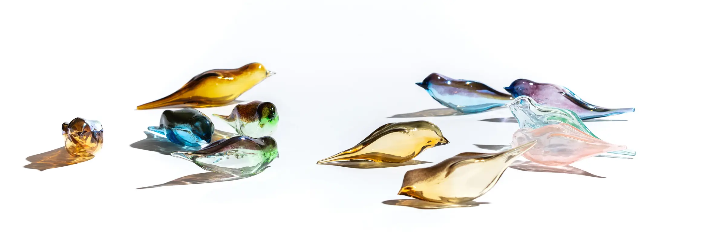 Gläserne, bunte Vögel vor einem weißen Hintergrund