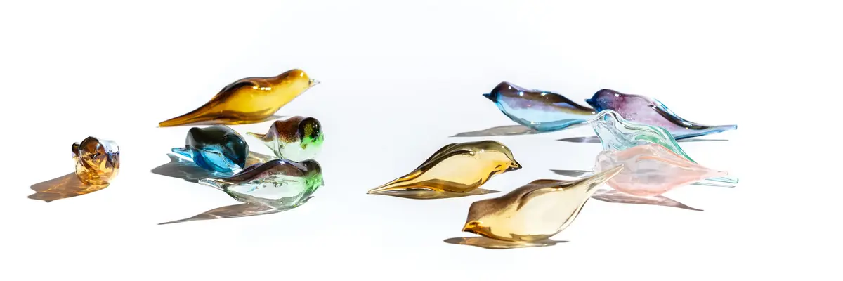 Gläserne, bunte Vögel vor einem weißen Hintergrund