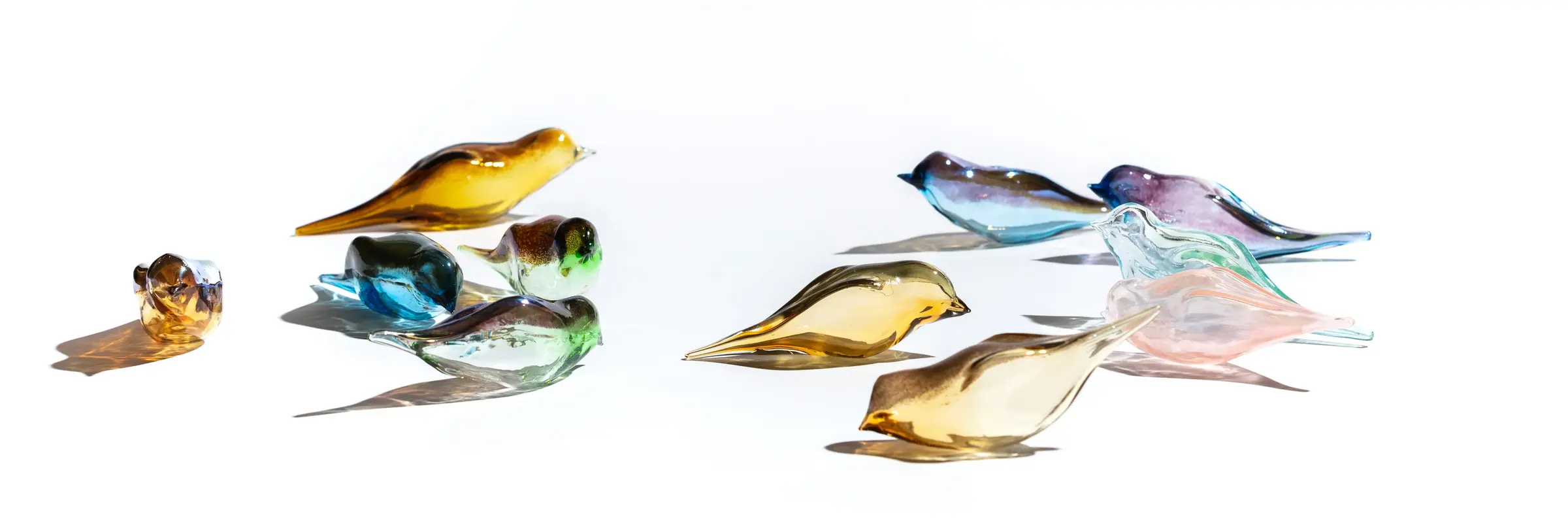 Gläserne, bunte Vögel vor einem weißen Hintergrund
