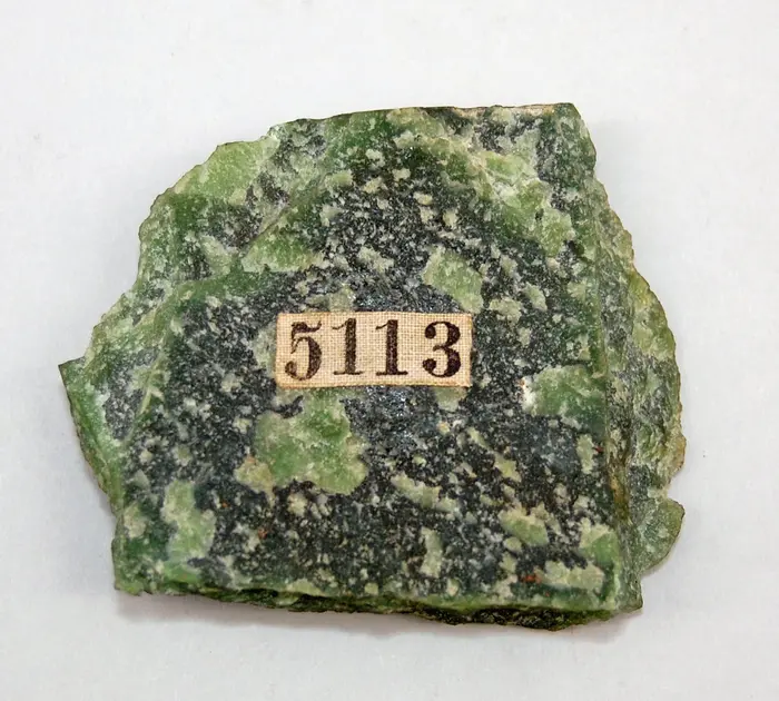 Teil eines grünen Gesteins mit aufgeklebter Nummer